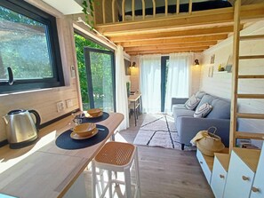 L’intérieur d’un chalet chaleureux, avec une table à manger en bois, un canapé et un escalier.