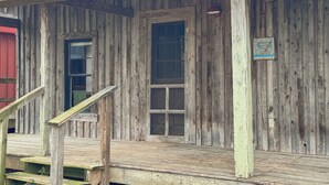 Een houten gebouw in rustieke stijl met een veranda, een deur en een raam.