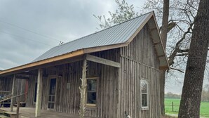 Een rustiek houten gebouw met veranda, een enkel raam en een metalen dak.