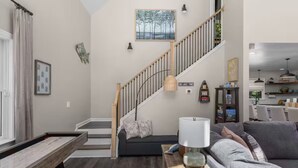 Un salon avec un escalier, un canapé, une lampe et une bibliothèque.