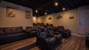 Ein Zimmer mit schwarzem Ledersofa, mehreren Massagesesseln und Holzboden.