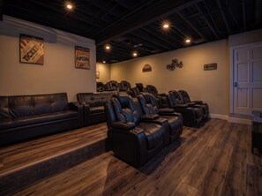 Ein Zimmer mit schwarzem Ledersofa, mehreren Massagesesseln und Holzboden.