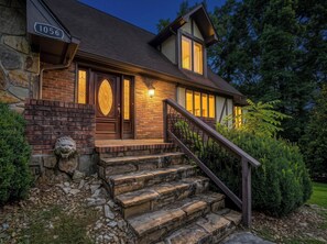 Ein Haus mit einer Stein-Fassade, einer Holztür und einer Treppe zum Eingang.