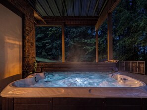 Un jacuzzi con vistas a un área boscosa a través de un ventanal grande.