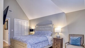 Ein Schlafzimmer mit einem Bett, Nachttischen, einem Sessel und einem Kleiderschrank.