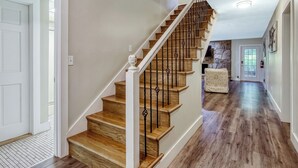 Eine Treppe mit Holzboden und Metallgeländern, die zu einer Zwischenebene mit einer Wand aus Steinplatten führt.