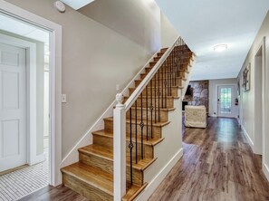 Eine Treppe mit Holzboden und Metallgeländern, die zu einer Zwischenebene mit einer Wand aus Steinplatten führt.