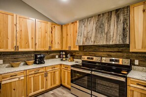 A kitchen with wooden cabinets, a stainless steel stove, and a coffee maker. - Big Bear Lodge | Sleeps 28 | Mtn Views + Hot Tub (Sevierville)