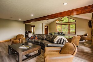 A spacious living room with a leather sectional sofa, a coffee table, and leather armchairs. - Big Bear Lodge | Sleeps 28 | Mtn Views + Hot Tub (Sevierville)