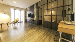 Een moderne woonkamer met een grote televisie, een bureau met een computer en een comfortabele fauteuil.