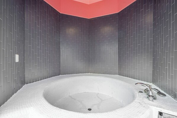 Ein modernes Badezimmer mit einer großen Badewanne, gefliesten Wänden und einer roten Decke.