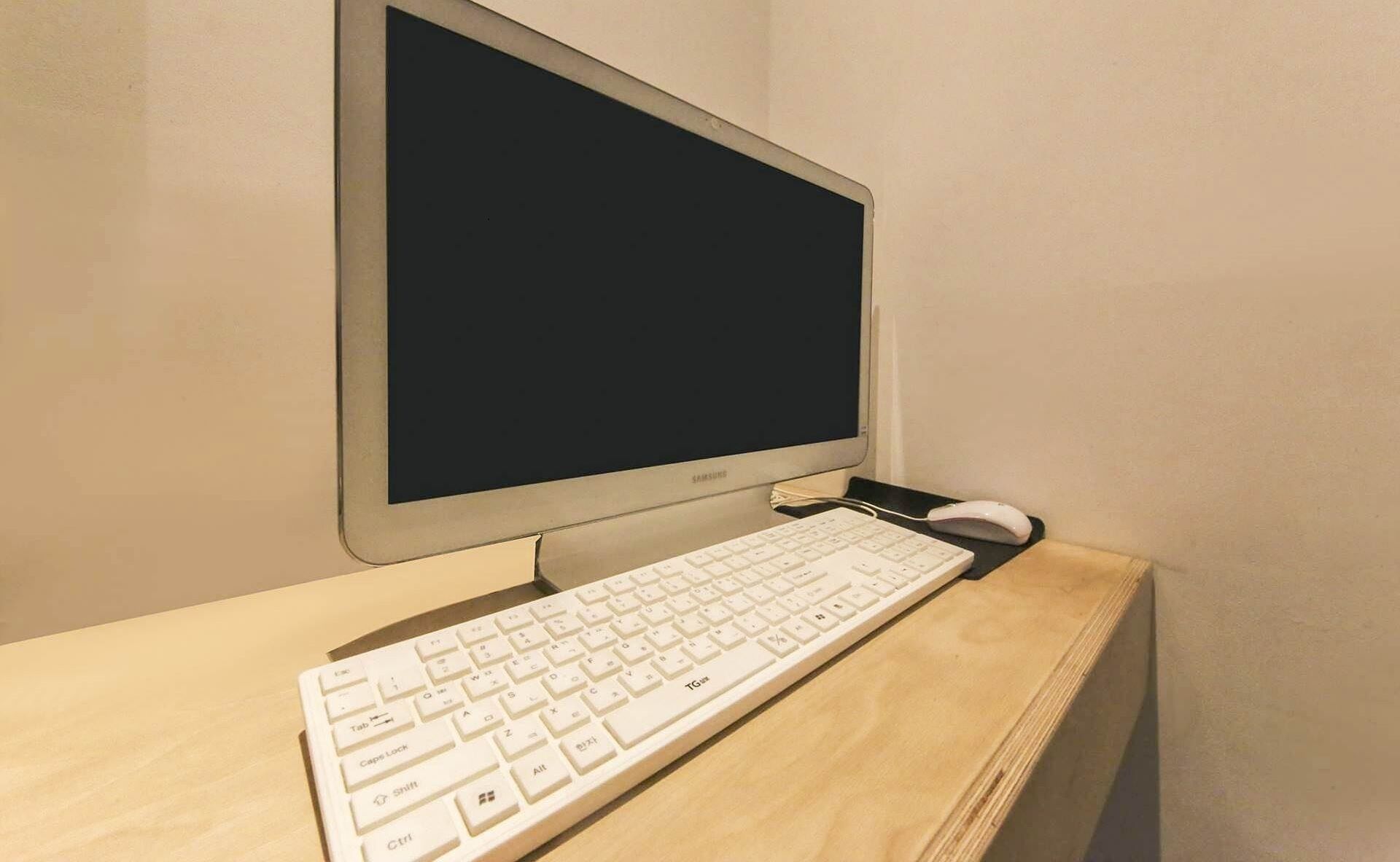 A desktop computer with a keyboard and a mouse on a wooden desk.