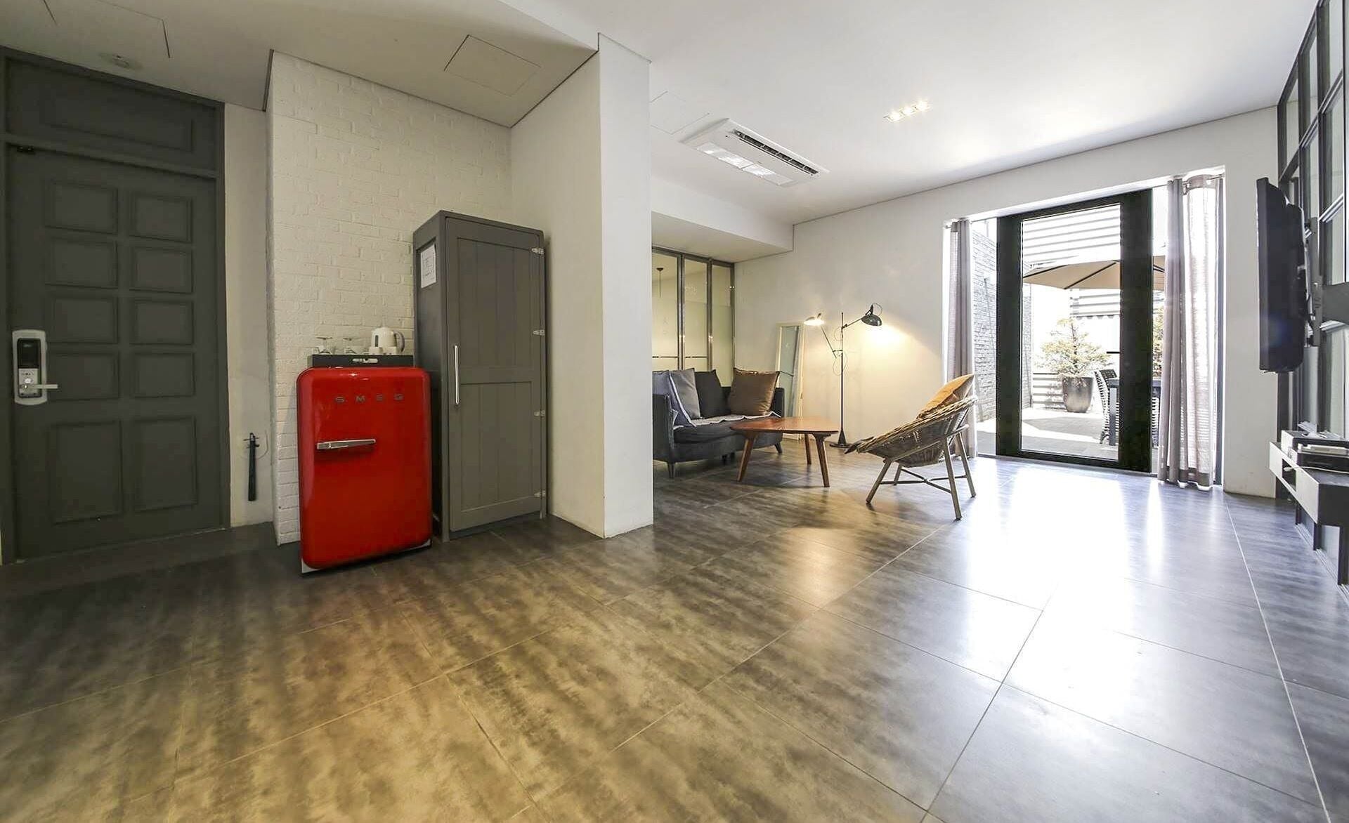 A modern living room with a red refrigerator, a sofa, a coffee table, and a chair.