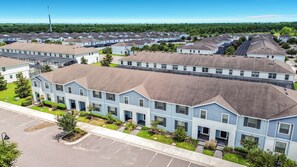 Un quartier résidentiel composé de plusieurs maisons à deux étages, d’un parking et d’un grand bâtiment doté d’un toit plat.