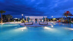 Piscina con una zona de estar central y una estructura de juegos para niños.