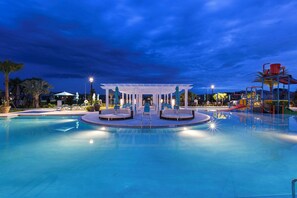 A swimming pool with a central seating area and a children's play structure.