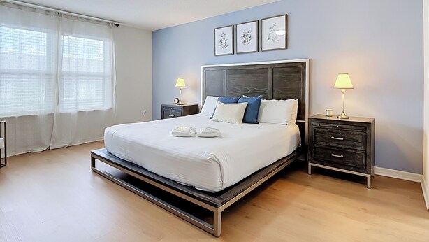 A modern bedroom with a bed, bedside tables, and a window with curtains.