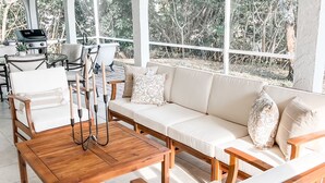 Une vaste terrasse dotée d’une table en bois, de sièges confortables et d’un barbecue.
