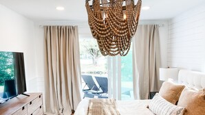 Une chambre moderne avec un grand lit, une commode en bois et un téléviseur posé sur un meuble.