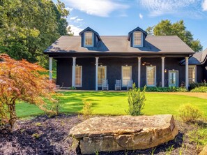 A two-story house with a dark exterior, a sloped roof, and a front porch with white columns.