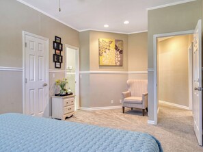 Une chambre à coucher avec un lit, une commode, une chaise et un tableau accroché au mur.