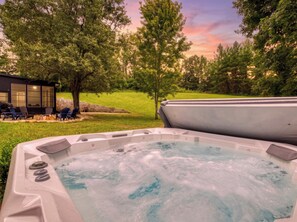 A hot tub with a grassy area and trees in the background. - Bella Vista, Perfect for Groups,  Indoor Pool, 12,000 Sq. Ft !!! (Sevierville)