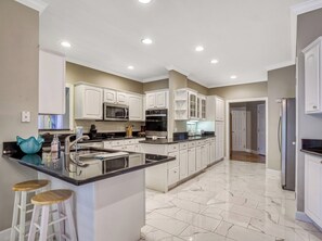 A modern kitchen with white cabinetry, a marble countertop, and a built-in oven. - Bella Vista, Perfect for Groups,  Indoor Pool, 12,000 Sq. Ft !!! (Sevierville)