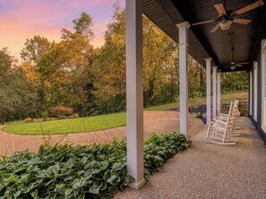 A covered outdoor area with a gravel path, green plants, and wooden rocking chairs. - Bella Vista, Perfect for Groups,  Indoor Pool, 12,000 Sq. Ft !!! (Sevierville)
