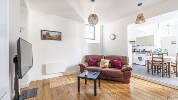 A modern living room with a leather sofa, a coffee table, a flat-screen TV, and a dining area with a table and chairs. - Cœur de Pau - Parking included - L'Étoile (Pau)