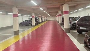 A multi-level parking garage with concrete pillars, a red floor, and several parked cars. - Cœur de Pau - Parking included - L'Étoile (Pau)