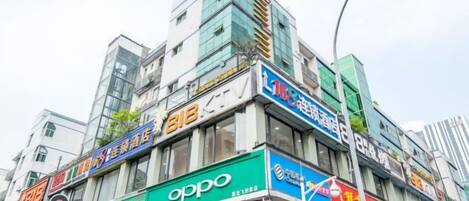Un edificio comercial de varios pisos con diversas fachadas, incluyendo un llamativo letrero verde que dice 'oppo'.
