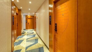 A hotel hallway with wooden doors, a patterned carpet, and a ceiling with recessed lighting. - 168 Chain Hotel (Shenzhen Liantang Metro Station) (Shenzhen)