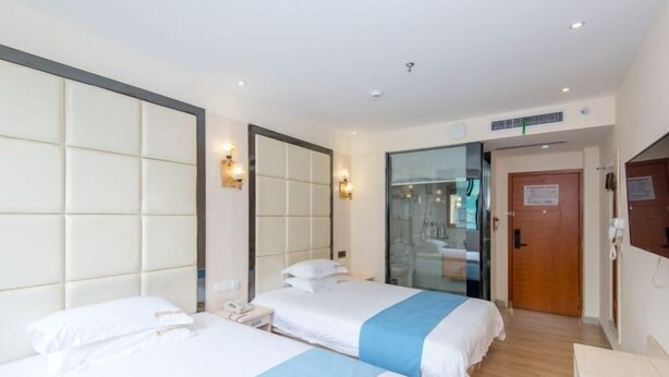 A hotel room with two beds, a large mirror, a wooden door, and a small desk with a telephone. - 168 Chain Hotel (Shenzhen Liantang Metro Station) (Shenzhen)
