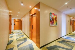A hotel hallway with patterned carpet, wooden doors, and a colorful painting on the wall. - 168 Chain Hotel (Shenzhen Liantang Metro Station) (Shenzhen)