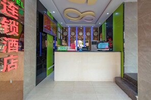 A hotel reception area with a reception desk, a digital screen, and a wall with clocks.