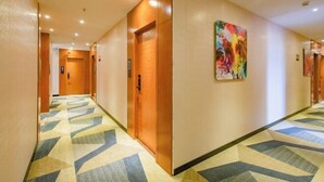 A hotel corridor with a geometric patterned carpet, wooden doors, and a colorful abstract painting on the wall. - 168 Chain Hotel (Shenzhen Liantang Metro Station) (Shenzhen)