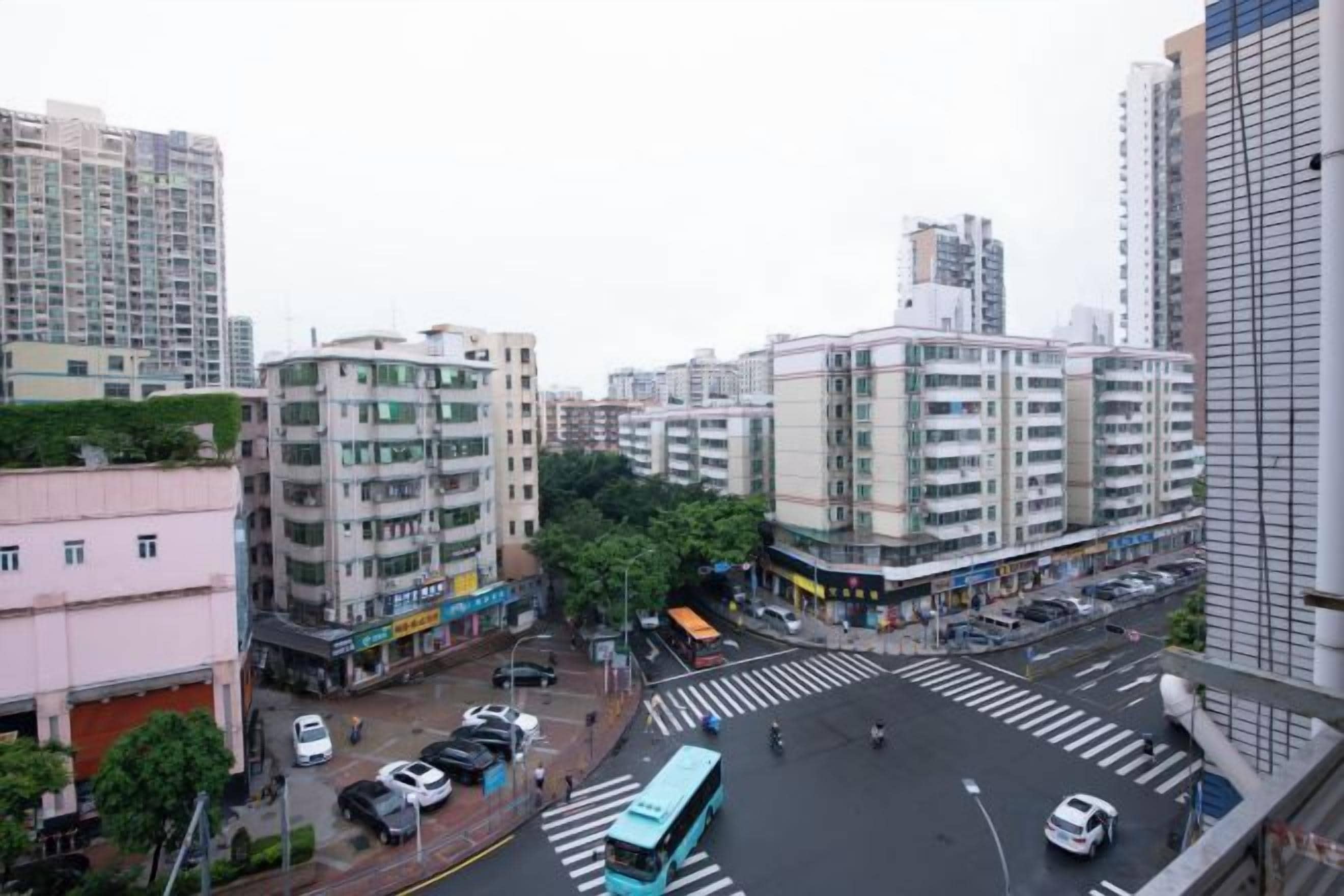 A cityscape with multi-story buildings, a crosswalk, and a bus.