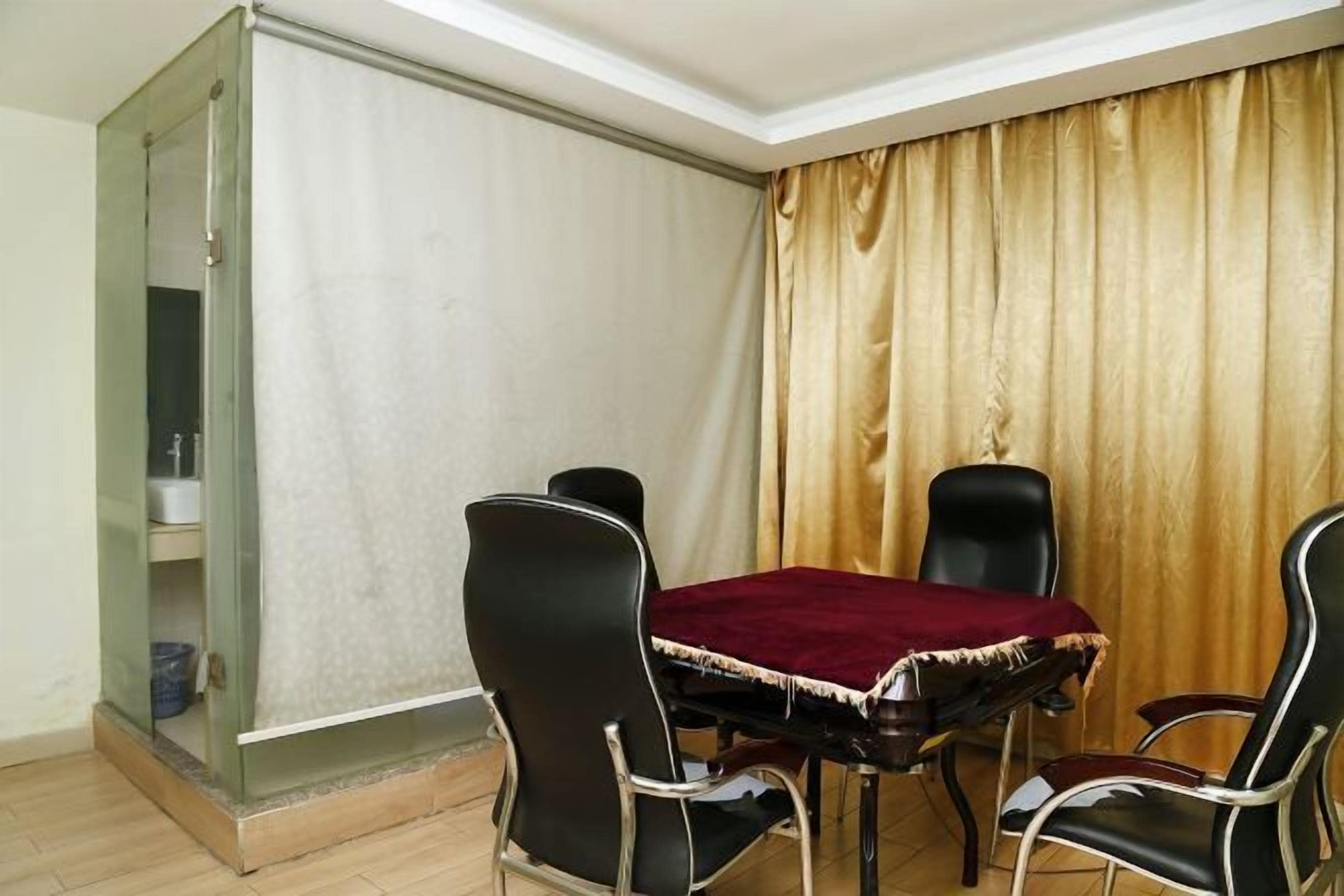 Uma área de refeições com uma mesa e quatro cadeiras, toalha de mesa vermelha e uma cortina.