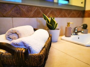 A wicker basket with folded towels, a potted plant, and a bathroom sink. - Playa Plateada Beach House (Ensenada)