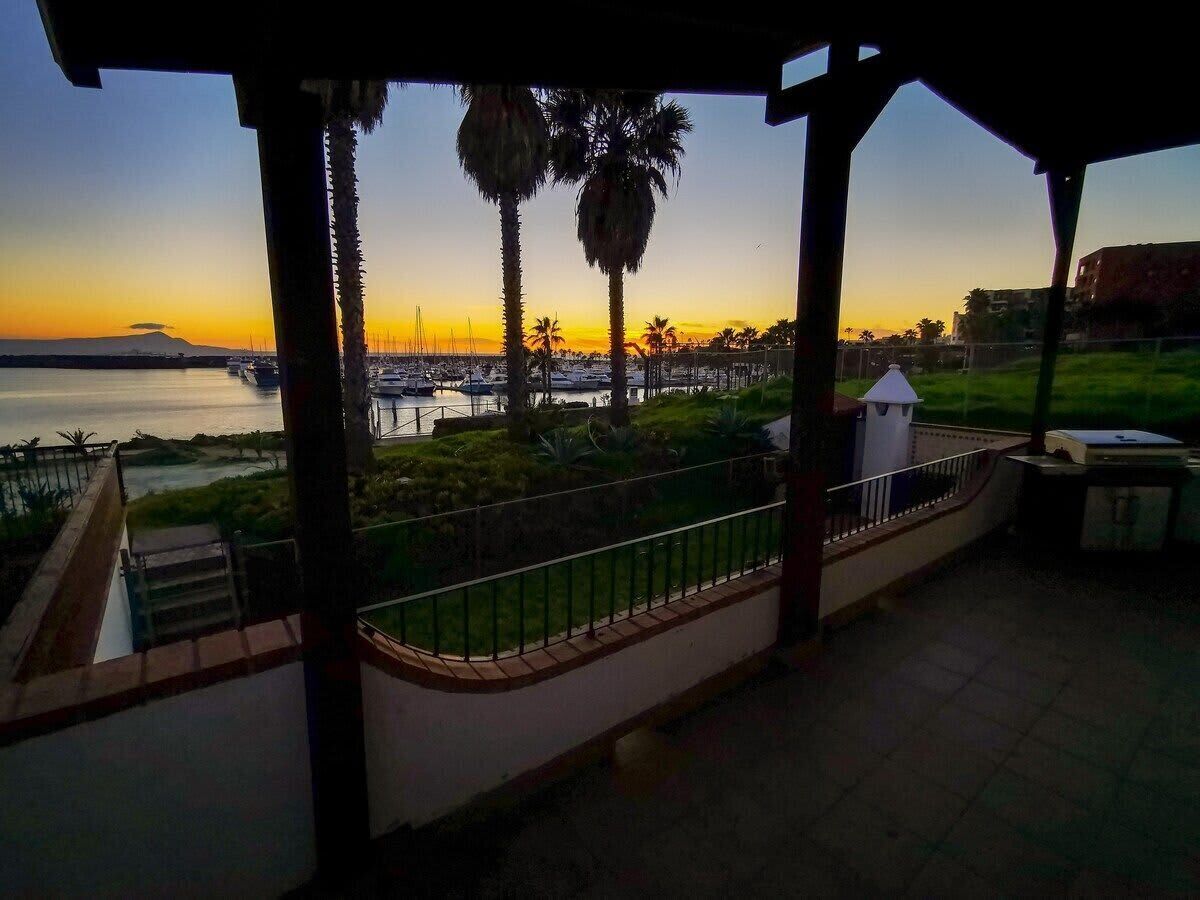 A covered outdoor area with a view of the marina and sunset.