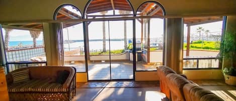A spacious room with a large glass door leading to an outdoor area, furnished with two sofas and a small table.