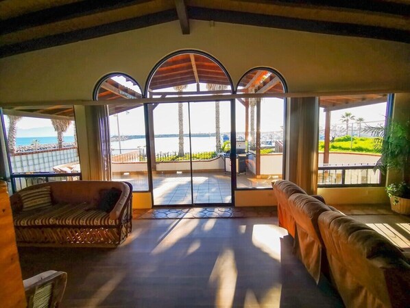 A spacious room with a large glass door leading to an outdoor area, furnished with two sofas and a small table. - Playa Plateada Beach House (Ensenada)
