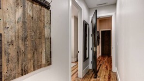 A hallway with wooden flooring, white walls, and a door leading to another room. - Cozy Downtown Asheville Condo | Walk everywhere (Asheville)