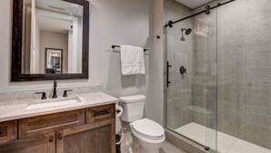 A modern bathroom with a glass-enclosed shower, a wooden vanity, and a large mirror. - Cozy Downtown Asheville Condo | Walk everywhere (Asheville)