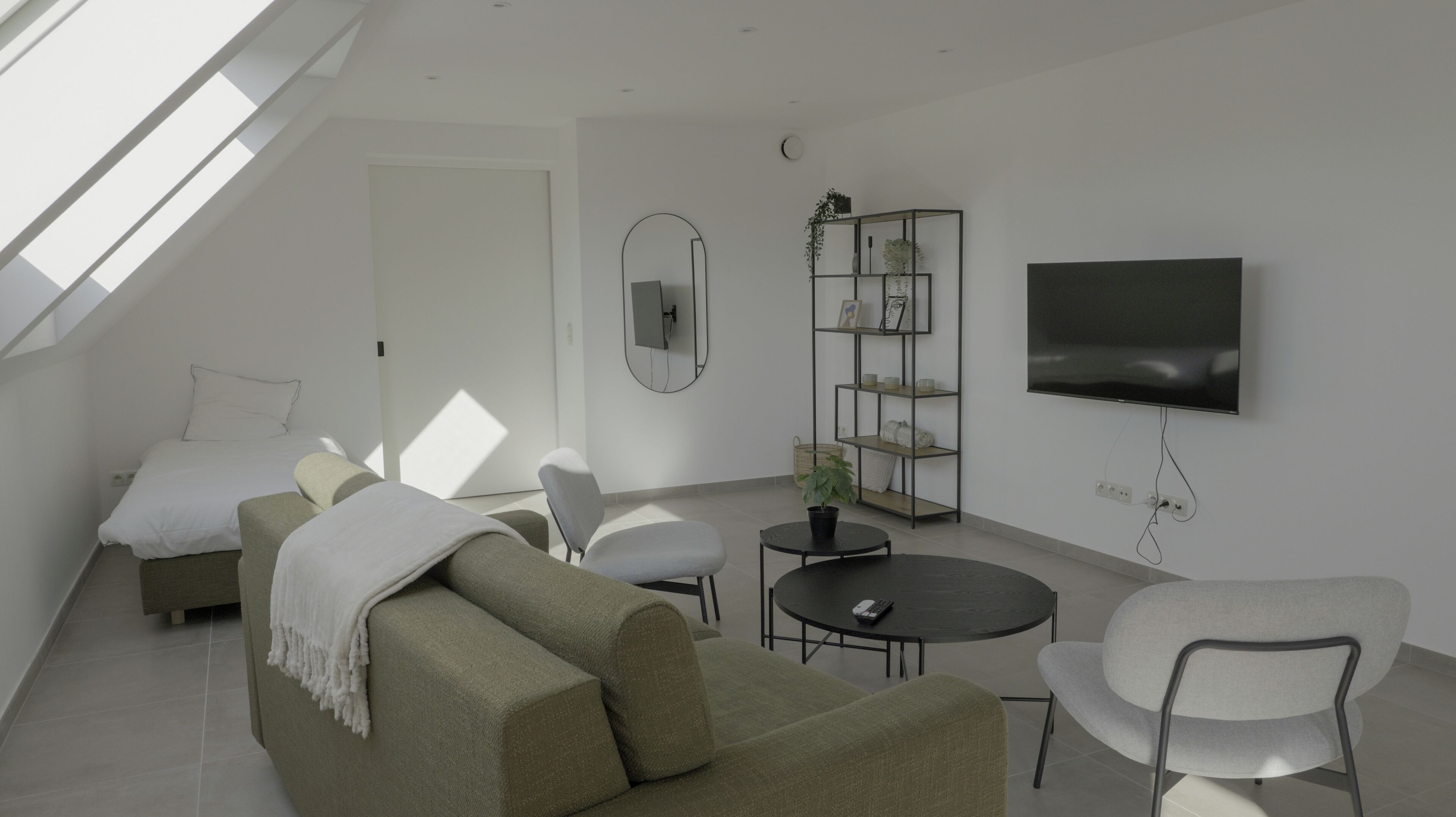 Una sala de estar moderna con un sofá, sillones, una mesa de centro, televisor y una estantería.