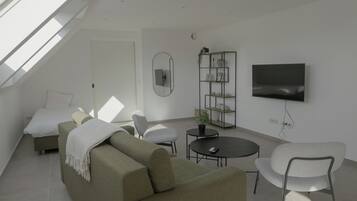 Una sala de estar moderna con un sofá, sillones, una mesa de centro, televisor y una estantería.