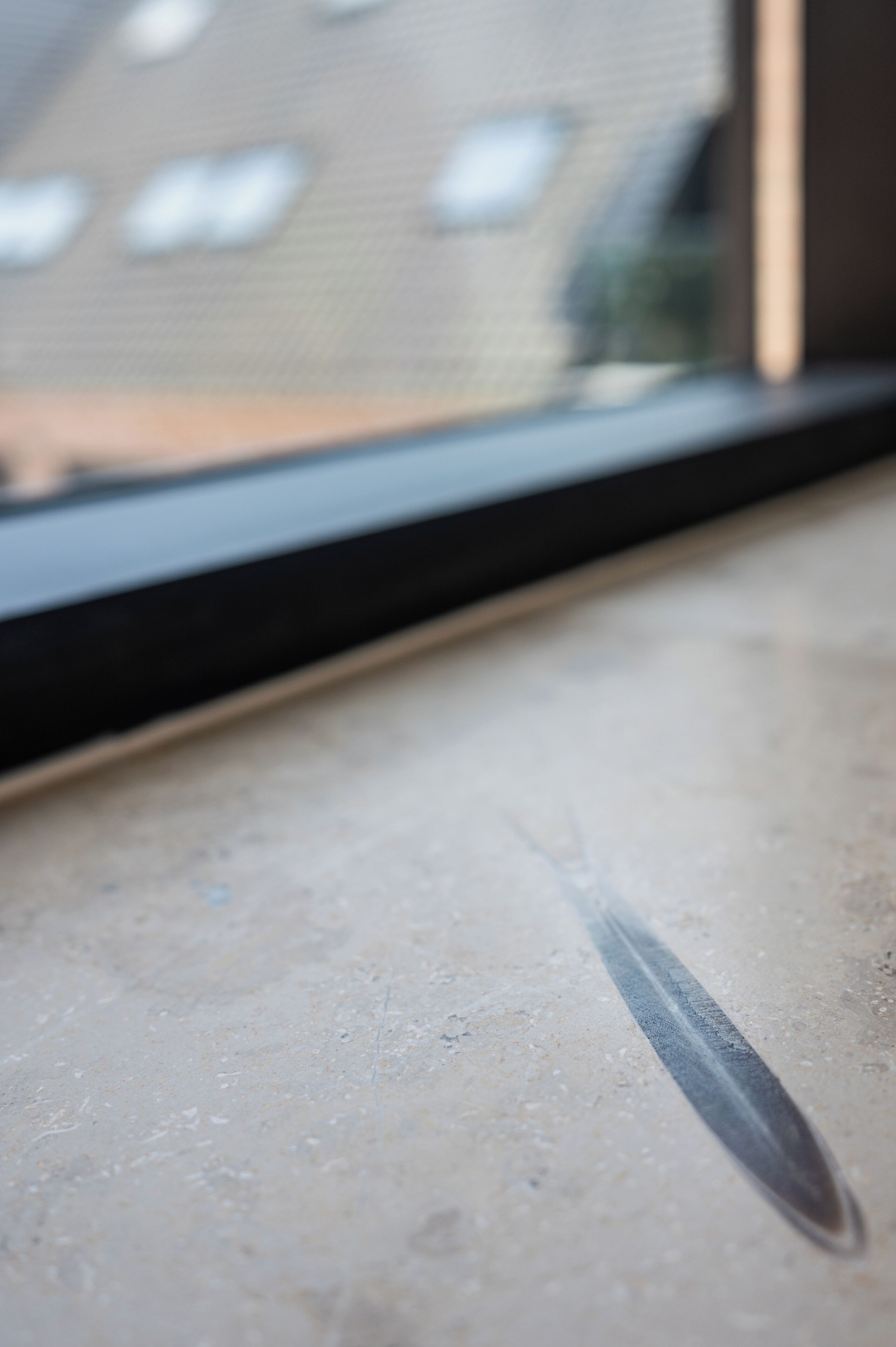 A close-up of a window sill with a knife blade resting on it.