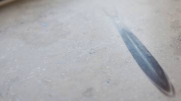 A close-up of a window sill with a knife blade resting on it.