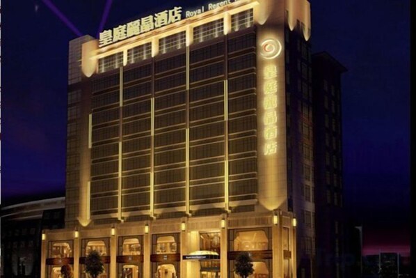 A hotel with a prominent sign at the top, multiple floors, and a well-lit facade.