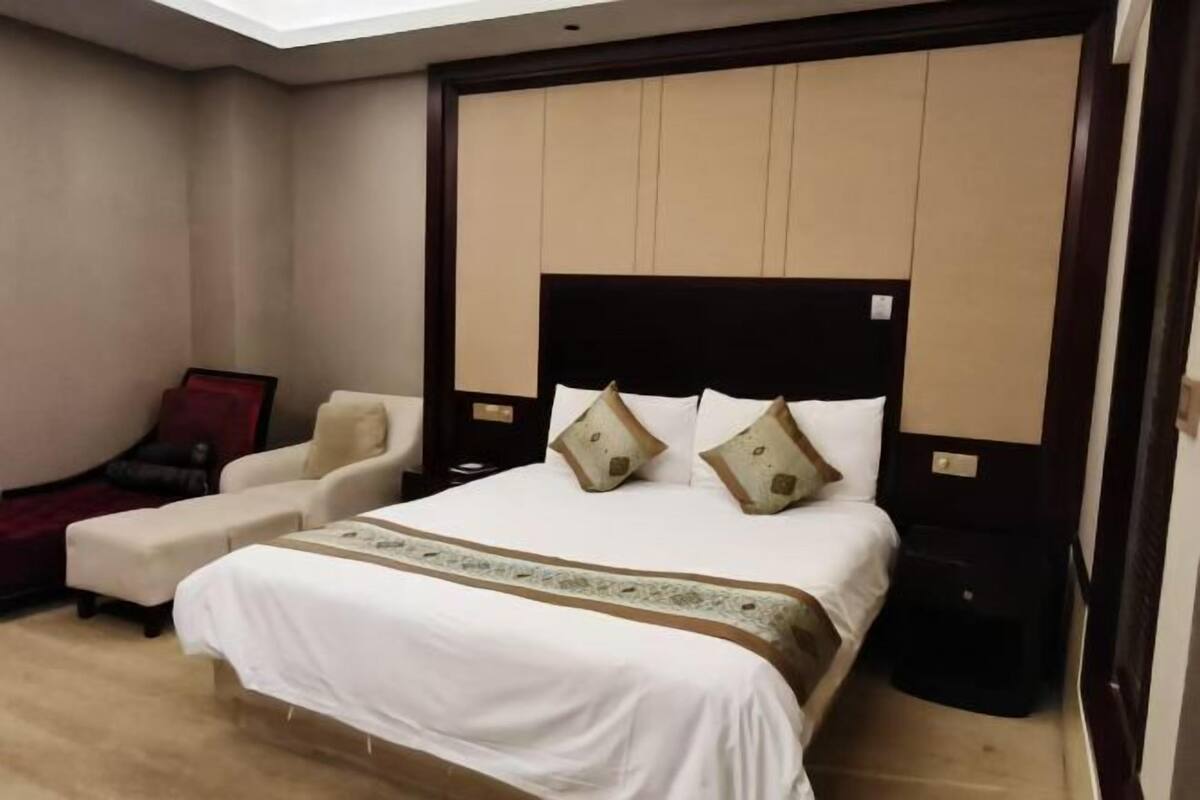 A hotel room with a bed, a sofa, a small table, and a red chair.